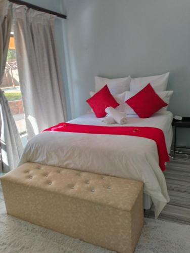 a bedroom with a large bed with red pillows at O&S BnB in Centurion