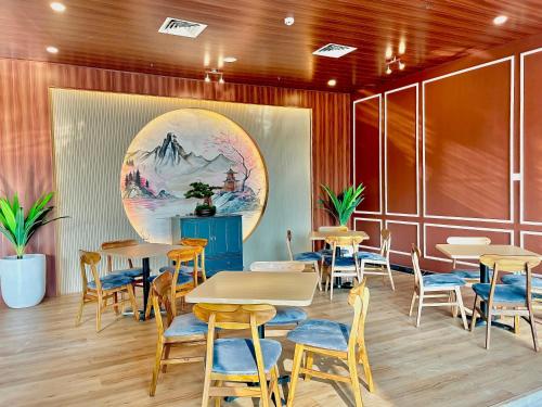 a restaurant with tables and chairs and a painting on the wall at Nemuru Grand Suites in Jakarta