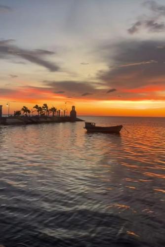 a boat in the water with a sunset at Hotel Casa Puerta de Mar in Campeche