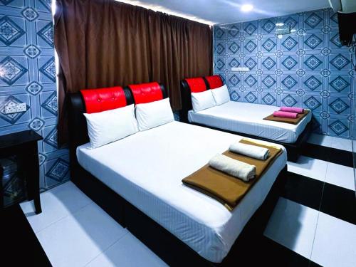two beds with red pillows in a room at ARK Hotel Taman Samudra in Kuala Lumpur