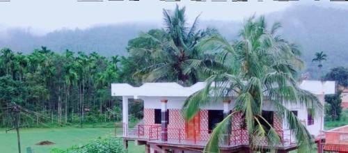 a house with two palm trees on top of it at Vamoose Suyoga Homestay Kudremukh in Kalasa