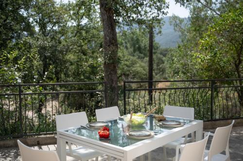 - une table et des chaises blanches avec vue sur la forêt dans l'établissement Villa Nature Argelès sur Mer, à Argelès-sur-Mer