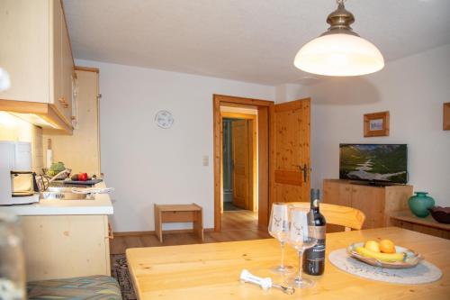 a kitchen with a wooden table with a bottle of wine at Ferienwohnungen Wolf in Holzgau