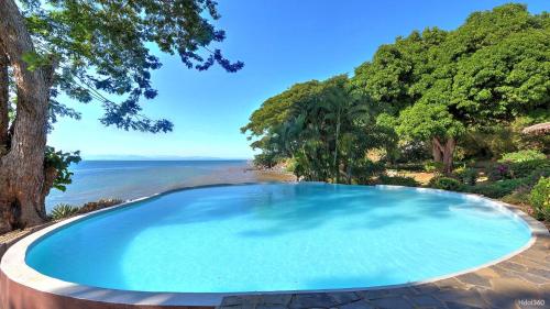 a large blue swimming pool next to a beach at Manga Soa Lodge in Fascène - Befefika