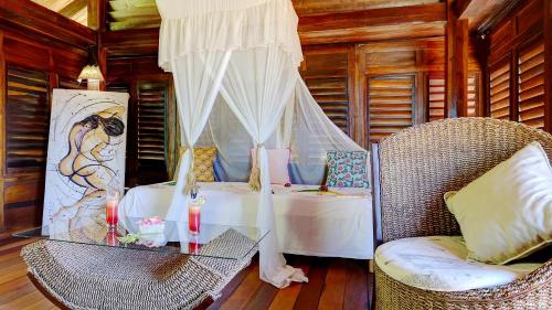 a bedroom with a bed and a glass table and chairs at Manga Soa Lodge in Fascène - Befefika