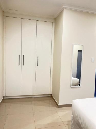 a white bedroom with white cabinets and a bed at Montrose BnB in Margate