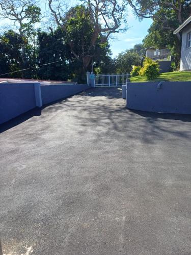 a parking lot with a blue fence and trees at Montrose BnB in Margate