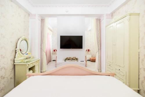 a bedroom with a white bed and a tv at 春漫小築民宿 in Miaoli