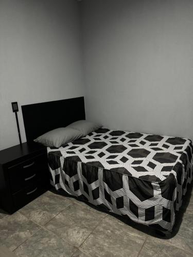 a bed with a black and white comforter in a bedroom at Loft en tequila Jalisco in Tequila