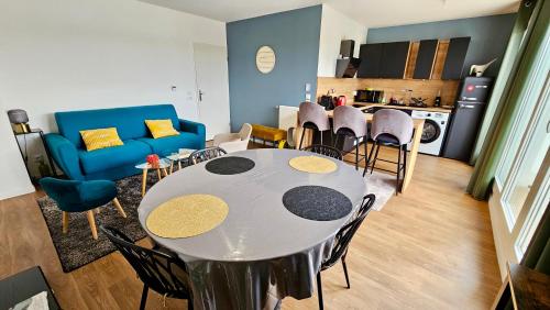 un salon avec une table et des chaises et une cuisine dans l'établissement Penthouse lumineux 20min Paris et Disney avec 2 balcons, à Noisiel