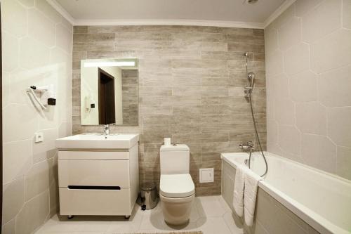 a bathroom with a toilet and a sink and a tub at Meridian in Karagandy