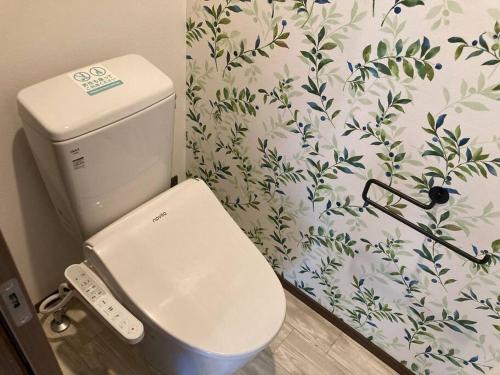 a white toilet in a bathroom with a flowery wallpaper at 藤田別荘 in Shodoshima
