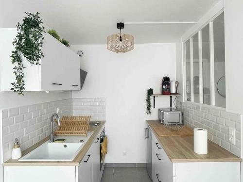 une cuisine avec des armoires blanches et un évier dans l'établissement T2 plein centre avec stationnement, à Bourgoin-Jallieu