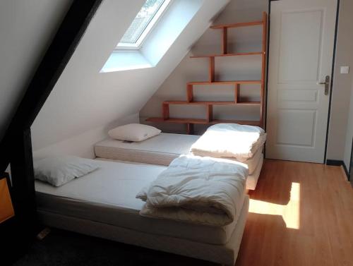 deux lits dans une chambre mansardée avec une fenêtre dans l'établissement Maison de campagne, proche plage, à Offrethun