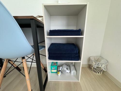 a white book shelf with blue towels and a desk at プレストスクエア松島町 in Takamatsu