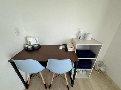 a wooden desk with two chairs and a telephone at プレストスクエア松島町 in Takamatsu
