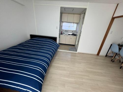 a bedroom with a blue and white bed and a kitchen at プレストスクエア松島町 in Takamatsu