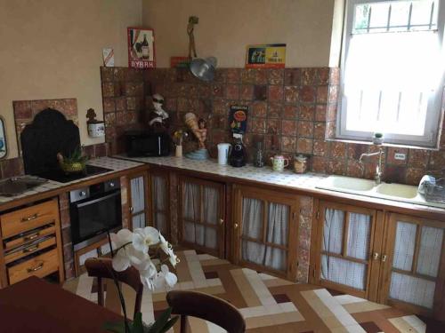 une cuisine avec des armoires en bois, une table et une fenêtre dans l'établissement Bourgogne grande maison avec jardin à la française, à Pontailler-sur-Saône