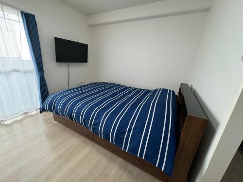 a bedroom with a bed with a television on the wall at プレストスクエア松島町 in Takamatsu