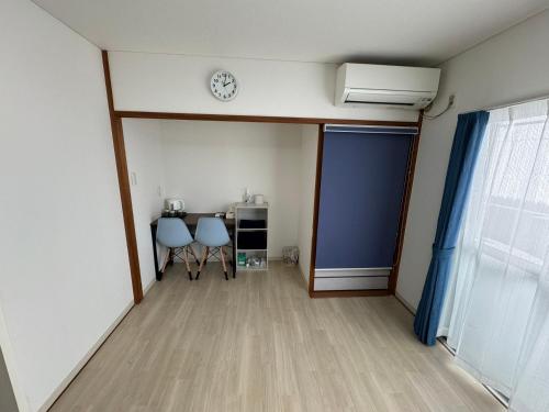 a room with two chairs and a table and a clock at プレストスクエア松島町 in Takamatsu