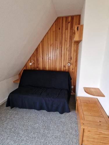 - une chambre mansardée avec un lit noir dans l'établissement Studio Le Gentiane, à Le Haut-Breda