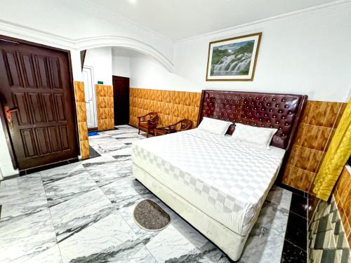 a bedroom with a bed and a wooden door at Hotel Grand Bandara in Medan