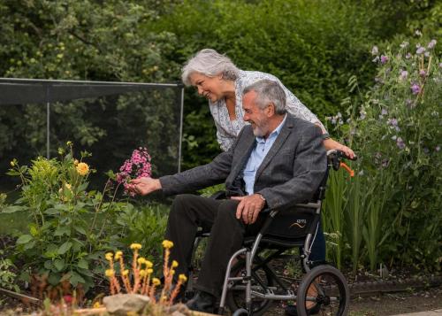an older man sitting in a wheelchair in a garden at Visaara Luxury Homes in Kammasandra