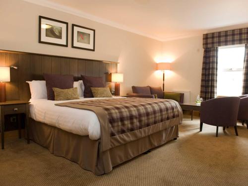 una camera d'albergo con un grande letto e una scrivania di Old Loans Inn a Troon