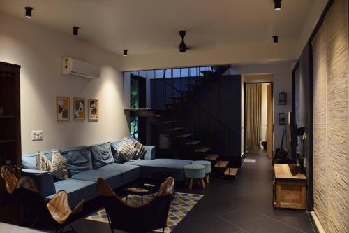 a living room with a blue couch and a staircase at The Hanging Villa - A Luxury Pool Villa in Jaipur in Jaipur