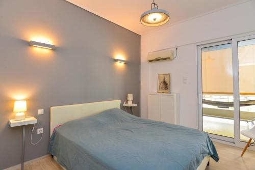 a bedroom with a blue bed and a window at Athenian Riviera Varkiza next to the beach in Vari