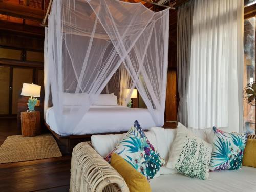 a bedroom with a bed and a couch with pillows at Full Moon Island Resort in Kaoh Sdach