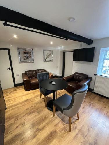 a living room with a table and leather furniture at Stepping Stones Cottage in Lealholm