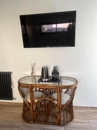 une table en verre avec une télévision sur un mur dans l'établissement Chambre indépendante avec jardin - 100m de la mer, à Langrune-sur-Mer