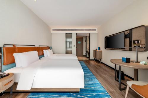 a hotel room with a large bed and a tv at Echarm Hotel Yichang East Railway Station in Yichang