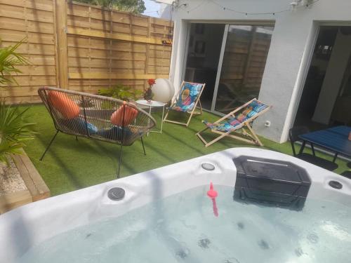 a hot tub in a yard with chairs and a table at Maison 4pers avec jacuzzi privatif couvert proche ocean in Brem-Sur-Mer