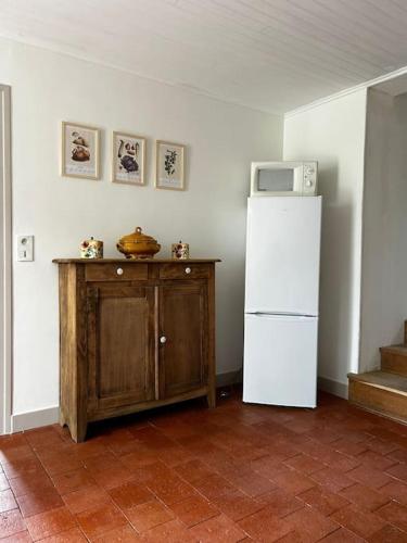 a kitchen with a white refrigerator and a wooden cabinet at Petite maison de charme à Thury in Thury