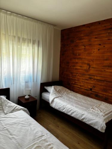 a bedroom with two beds and a wooden wall at Apartman Mila in Žabljak
