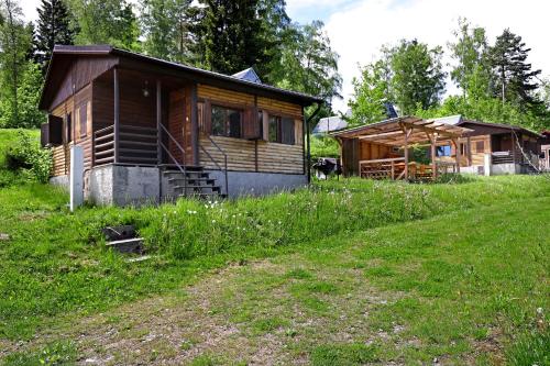 a wooden cabin in a field next to a grass field at Lipno Lodge in Horní Planá