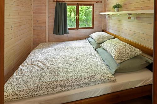 a bed in a log cabin with a window at Lipno Lodge in Horní Planá