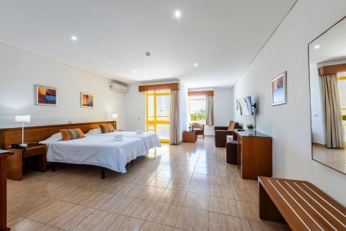 a hotel room with a bed and a living room at Hotel Pinhal do Sol in Quarteira