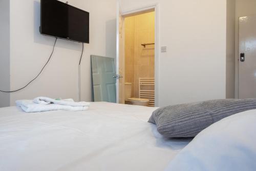 a bedroom with a white bed with a television on the wall at Pebbles guest house room 6 in Southampton