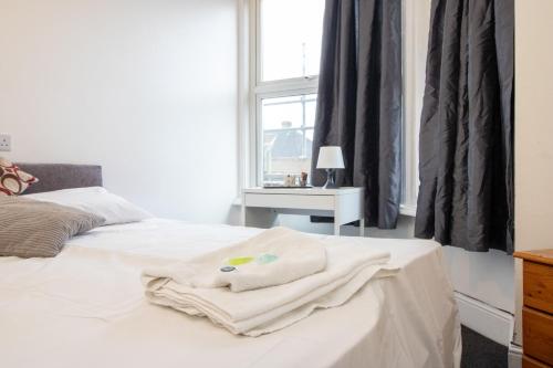 a white bed with a pile of towels on it at Pebbles guest house room 6 in Southampton