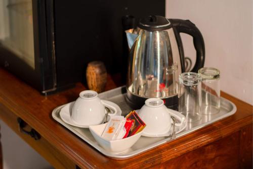 a tray with a tea kettle and cups on a counter at Sigiriya Cottage in Sigiriya
