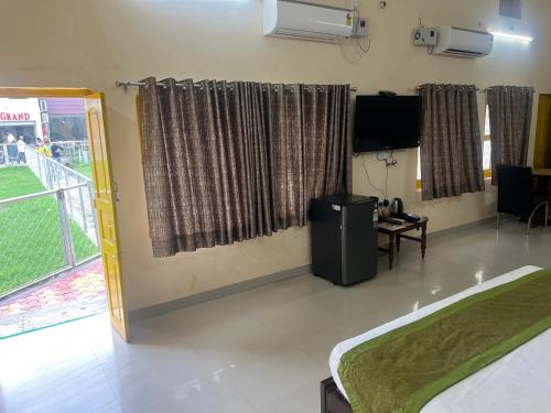 a room with a bed and a television and a window at Hotel Utsav Grand in Varanasi