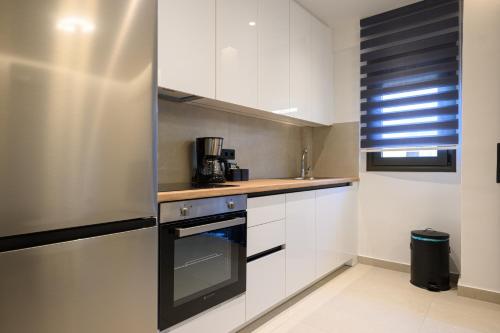 a kitchen with white cabinets and a stainless steel refrigerator at Hidden Gem by the Sea in Artemida