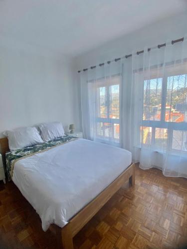 a white bedroom with a large bed and a window at Apartamento Bela Vista em Castro Daire in Castro Daire