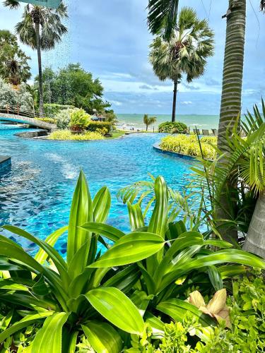 a swimming pool with palm trees and blue water at The Palm Wongamat 22 in North Pattaya