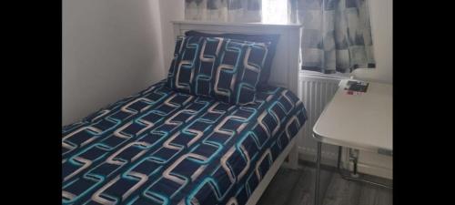 1 cama con edredón azul y blanco en una habitación en Elm Park Home with Garden & Parking, en Hornchurch