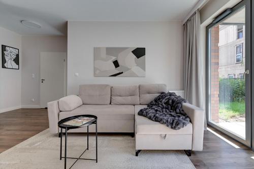 a white living room with a couch and a table at Scala City Center Apartments & Studio by Lion Apartments in Gdańsk