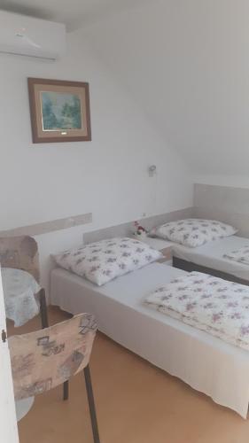 a room with three beds and a chair and a picture at Czinger Vendégszobák in Mosonmagyaróvár